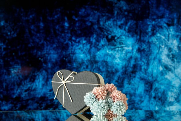 Vue de face de fleurs colorées de boîte de coeur noir sur le fond abstrait bleu-foncé