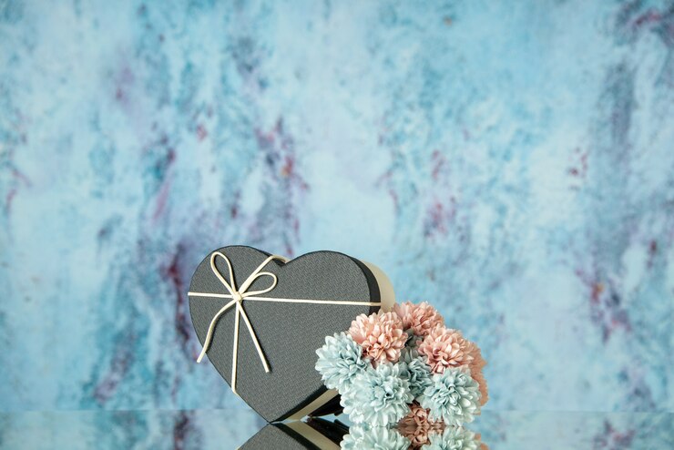 Photo gratuit vue de face de fleurs colorées en forme de coeur noir reflétées sur un miroir avec un bleu