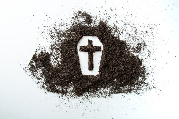 Vue de face de la forme de cercueil avec de la terre brune sur la mort funéraire de bureau blanc