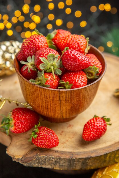 Vue de face des fraises fraîches autour des jouets de noël sur fond sombre goût de fruits photo de noël sombre