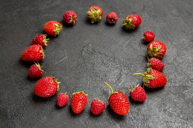 Vue de face fraises rouges fraîches bordées sur fond gris foncé