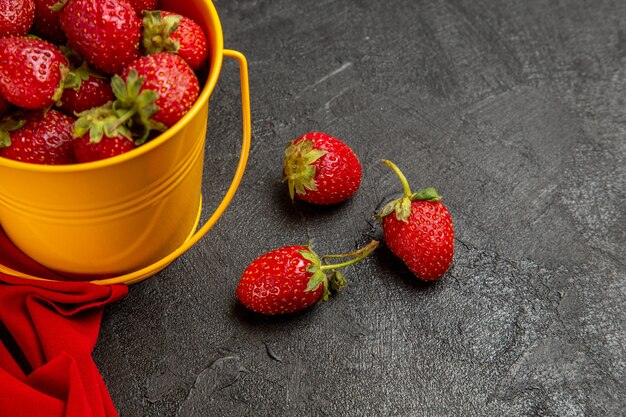 Vue de face fraises rouges fraîches à l'intérieur du petit panier sur le fond sombre