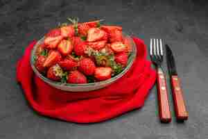 Photo gratuite vue de face fraises rouges fraîches à l'intérieur de la plaque avec des couverts sur fond sombre couleur d'été jus d'arbre baie sauvage