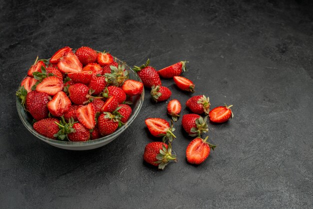 Vue de face fraises rouges tranchées et fruits entiers sur fond gris couleur d'été baie de jus d'arbre sauvage