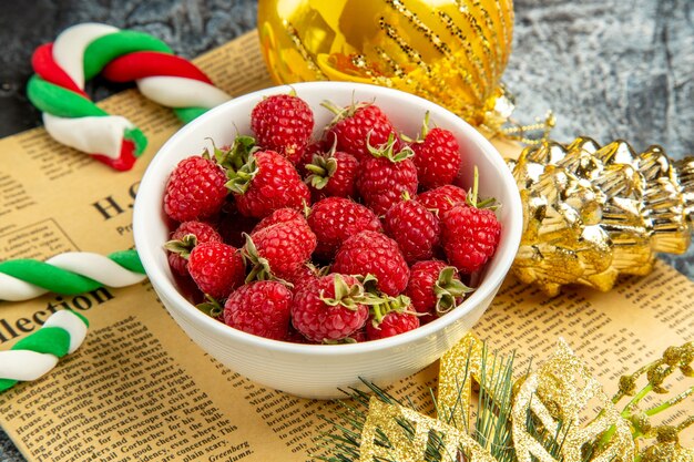 Vue de face de framboises fraîches avec des bonbons et des jouets