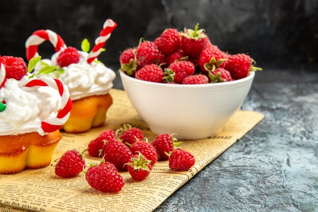 Vue de face de framboises fraîches avec des gâteaux