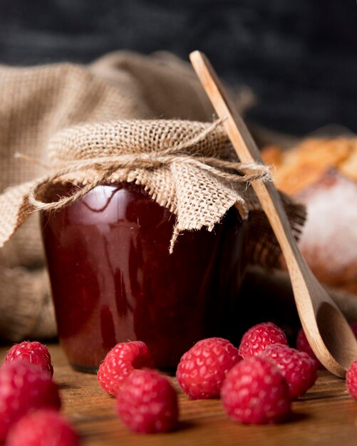 Vue de face de framboises avec pot de confiture