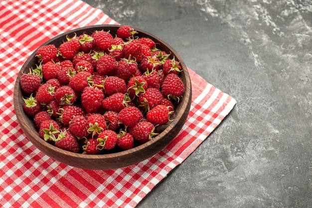 Vue de face framboises rouges fraîches à l'intérieur de la plaque sur fruits gris couleur canneberge photo sauvage berry