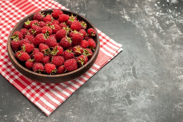 Vue de face de framboises rouges fraîches à l'intérieur de la plaque sur une photo de couleur de baies grises de fruits sauvages de canneberge