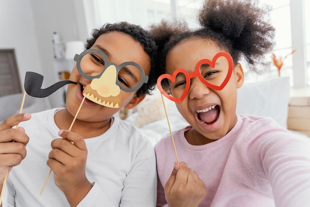 Vue de face des frères et sœurs prenant selfie à la maison