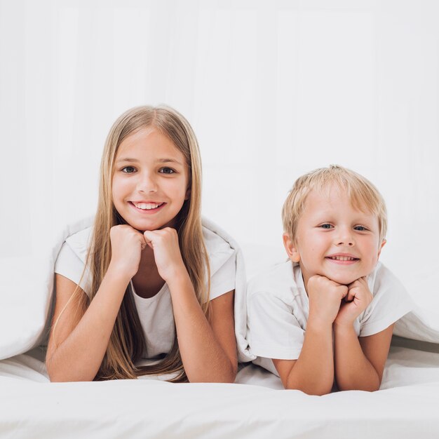 Vue de face des frères et soeurs souriants regardant la caméra