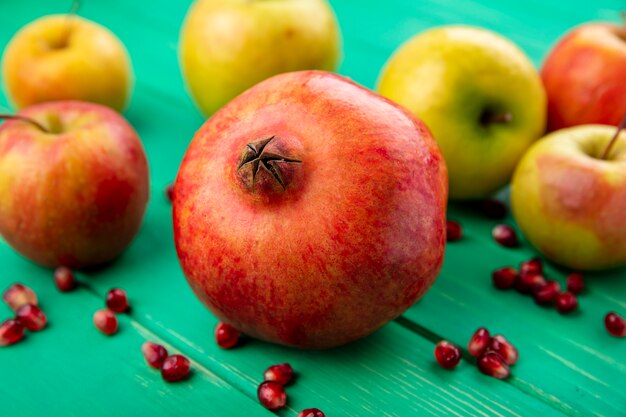 Vue de face des fruits comme la grenade et la pomme sur la surface verte