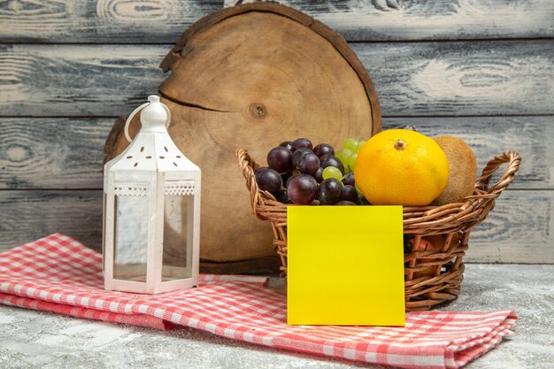 Vue de face des fruits frais à l'intérieur du panier sur la couleur du cahier d'agrumes de fruits de fond gris