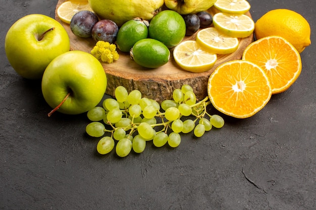 Vue de face fruits frais raisins tranches de citron prunes et coings sur fond sombre fruits frais mûrs plante arbre