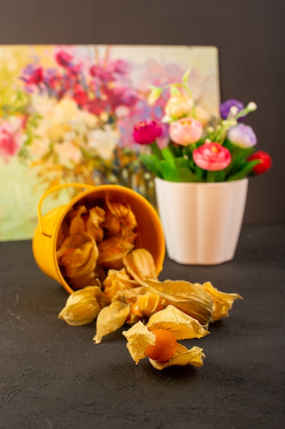 Une vue de face fruits orange à l'intérieur du panier jaune fruits ronds avec peinture et fleur sur gris