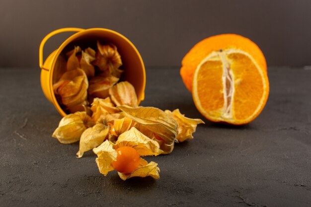 Une vue de face de fruits orange avec des pelures avec des tranches et des orange entiers sur dark