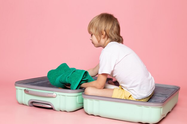 vue de face garçon blond à l'intérieur du sac bleu sur rose