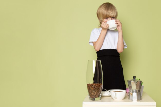 Une vue de face garçon blond en t-shirt blanc, boire du café sur l'espace de couleur pierre