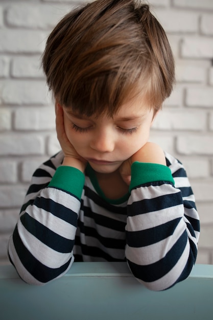 Photo gratuite vue de face garçon triste assis à l'intérieur