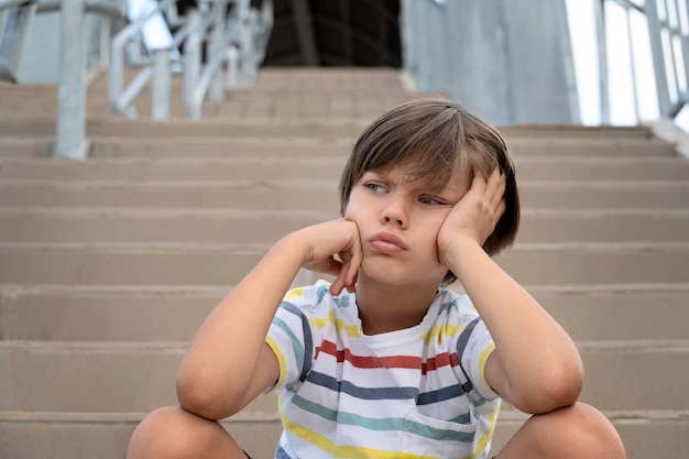 Photo gratuite vue de face garçon triste dans les escaliers