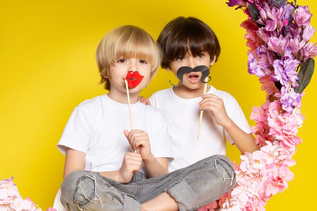 Une vue de face garçons mignons adorables en t-shirts blancs avec des moustaches sur l'espace jaune