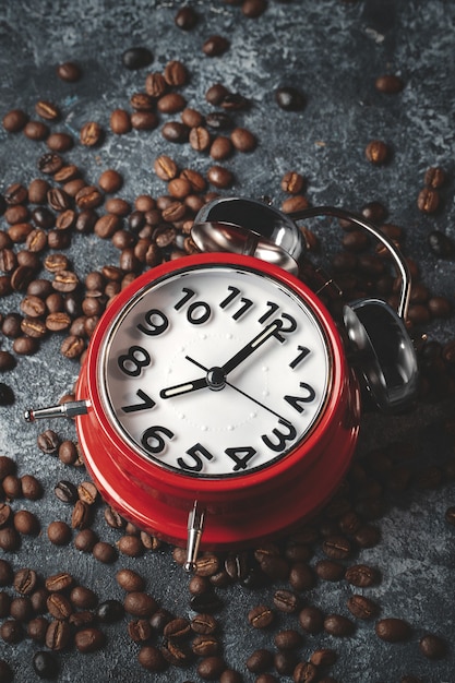 Vue de face des graines de café brun avec horloges rouges surface sombre