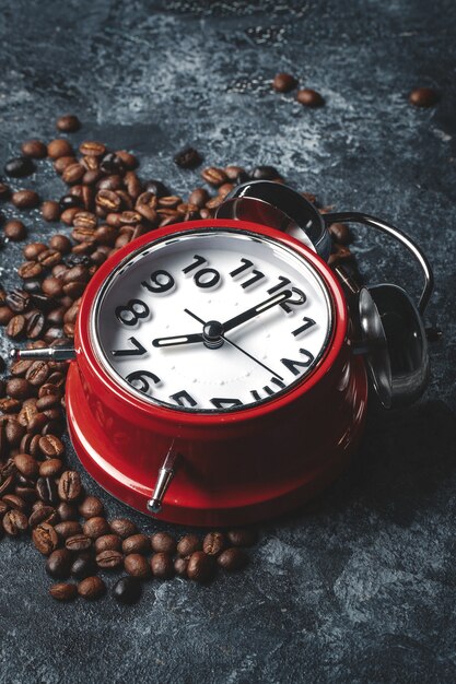 Vue de face des graines de café avec des horloges sur une surface sombre