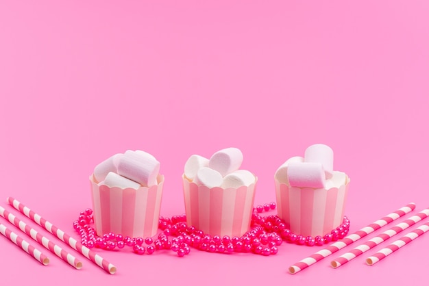 Une vue de face des guimauves blanches à l'intérieur des paquets de papier rose isolated on pink