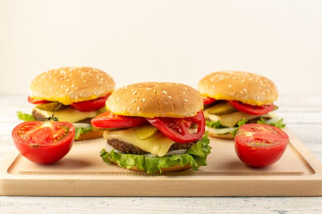 Une vue de face des hamburgers de poulet avec du fromage et de la salade verte sur le bureau en bois et un sandwich restauration rapide