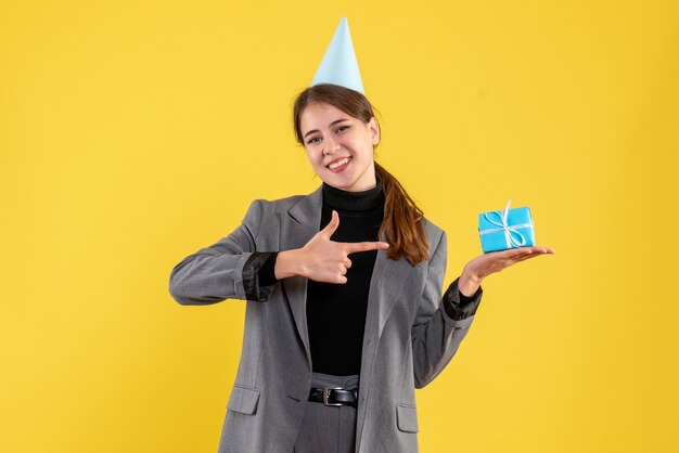 Vue de face heureuse jolie fille avec chapeau de fête tenant son cadeau