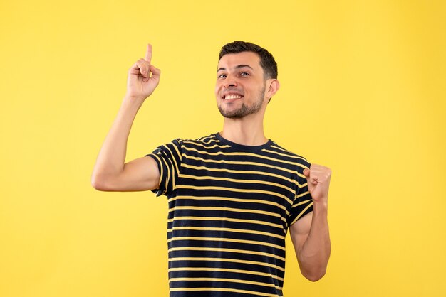 Vue de face heureux beau mâle en t-shirt rayé noir et blanc fond isolé jaune