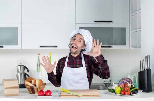 Vue de face heureux chef masculin ouvrant les mains dans la cuisine