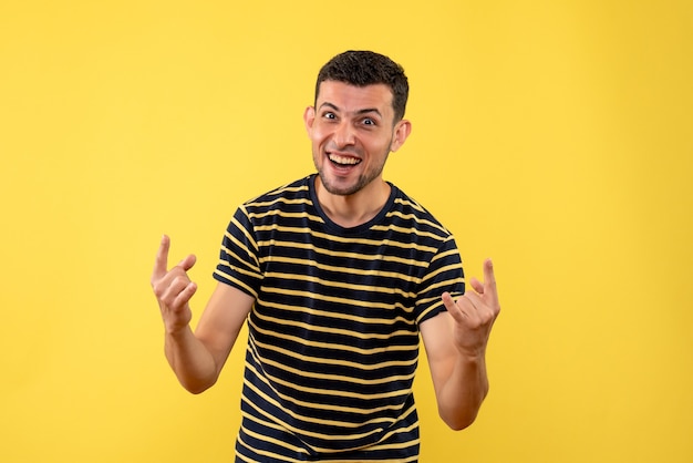 Vue de face heureux jeune homme en t-shirt rayé noir et blanc fond isolé jaune