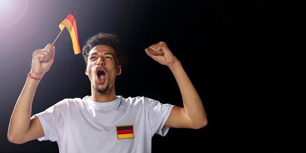 Vue de face de l'homme acclamant tenant le drapeau allemand