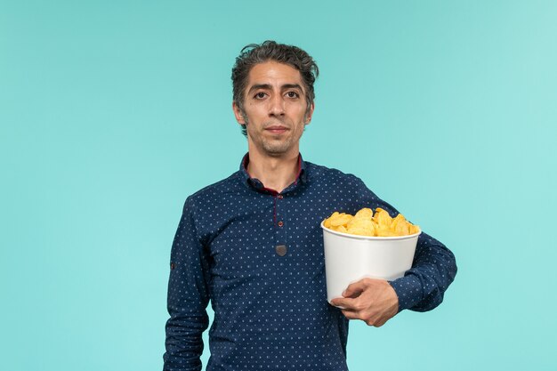 Vue de face homme d'âge moyen avec panier plein de cips sur la surface bleue