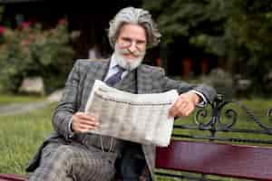 Photo gratuite vue de face homme d'âge mûr à la mode lisant le journal