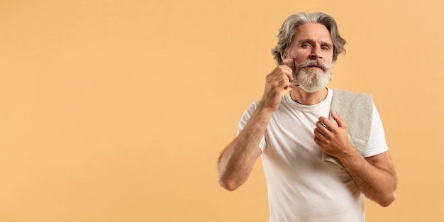 Vue de face d'un homme âgé se peignant la barbe