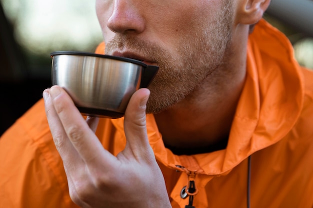 Vue de face de l'homme appréciant une boisson chaude lors d'un voyage sur la route