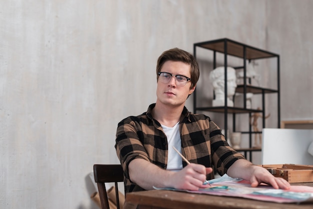 Photo gratuite vue de face homme artiste pensant à quoi peindre avec copie espace