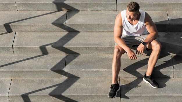 Vue de face homme assis dans les escaliers avec copie espace