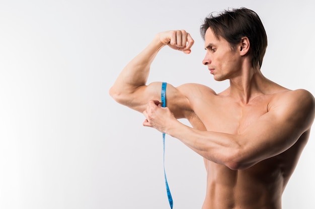 Vue de face de l'homme athlétique mesurant les biceps