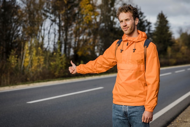 Vue de face de l'homme en auto-stop lors d'un voyage sur la route