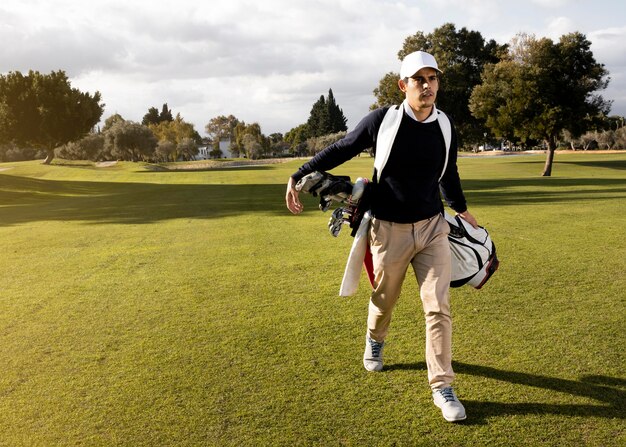 Vue de face de l'homme avec des clubs de golf sur le terrain