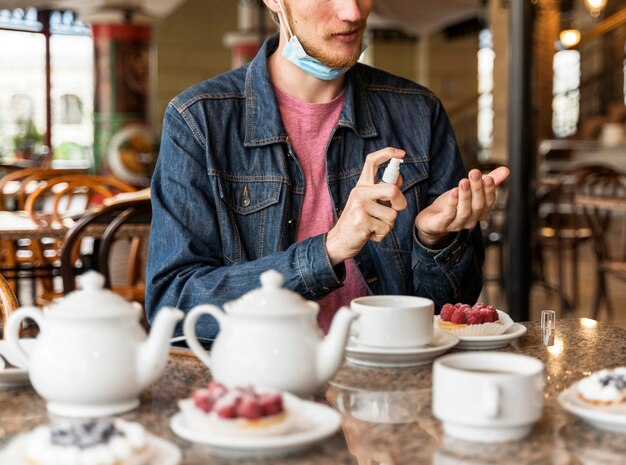 Vue de face homme désinfectant ses mains au restaurant