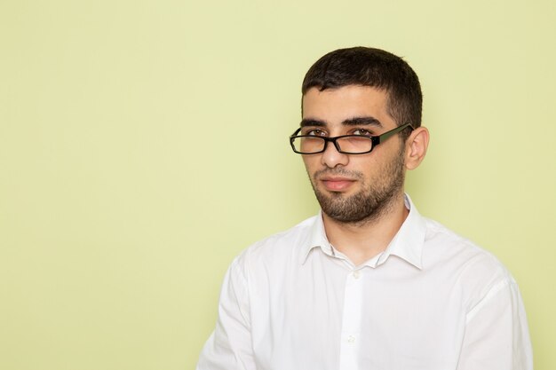 Vue de face de l'homme employé de bureau en chemise blanche juste debout sur le mur vert