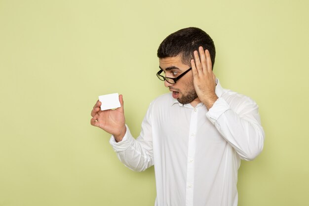 Vue de face de l'homme employé de bureau en chemise blanche tenant une carte sur le mur vert clair