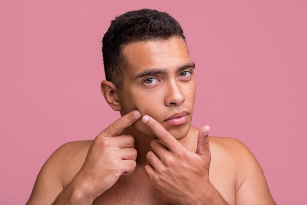 Vue de face de l'homme essayant de faire apparaître un bouton sur son visage