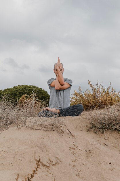 Vue de face de l'homme à l'extérieur de méditer tout en faisant du yoga