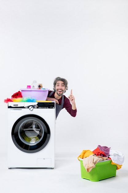 Vue de face homme de femme de ménage en tablier assis derrière le panier à linge lave-linge sur fond blanc