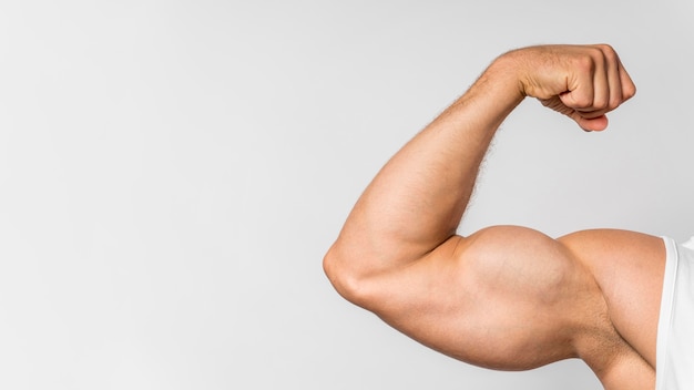Vue de face de l'homme en forme montrant les biceps avec copie espace